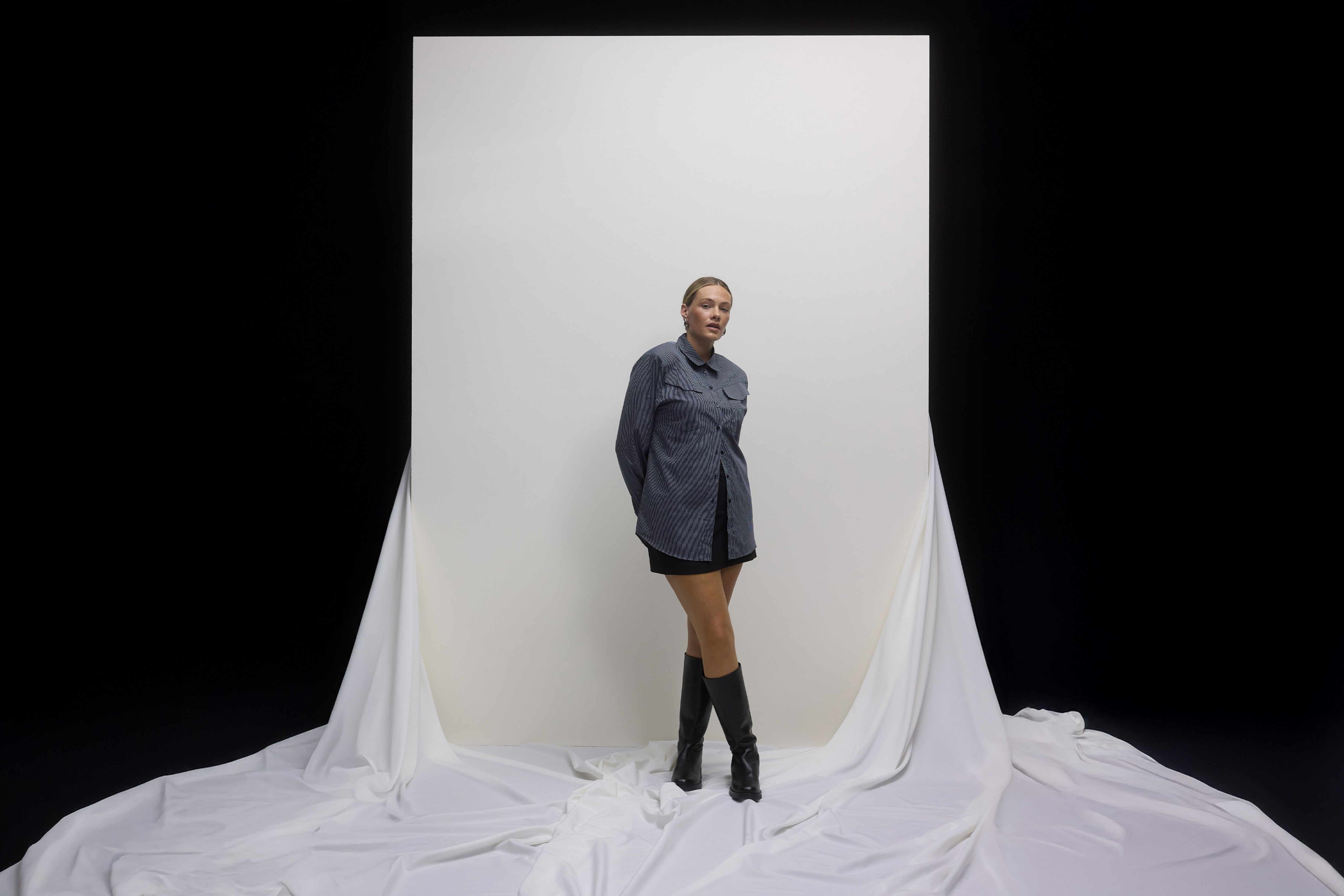 Frau mit gestreiftem Shirt, Minirock und Stiefeln.