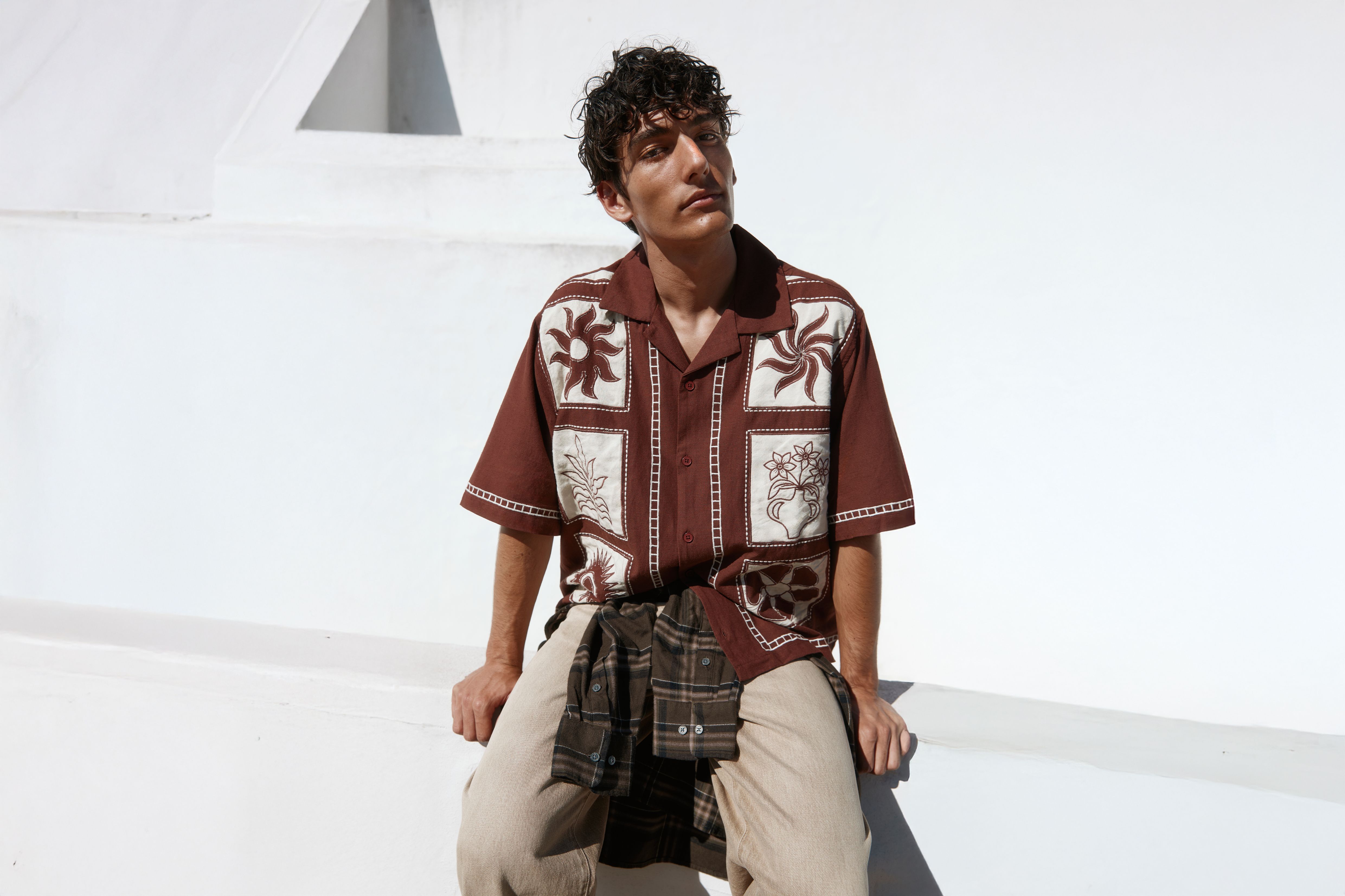 Mann sitzt und trägt ein braunes Kurzarm-Shirt